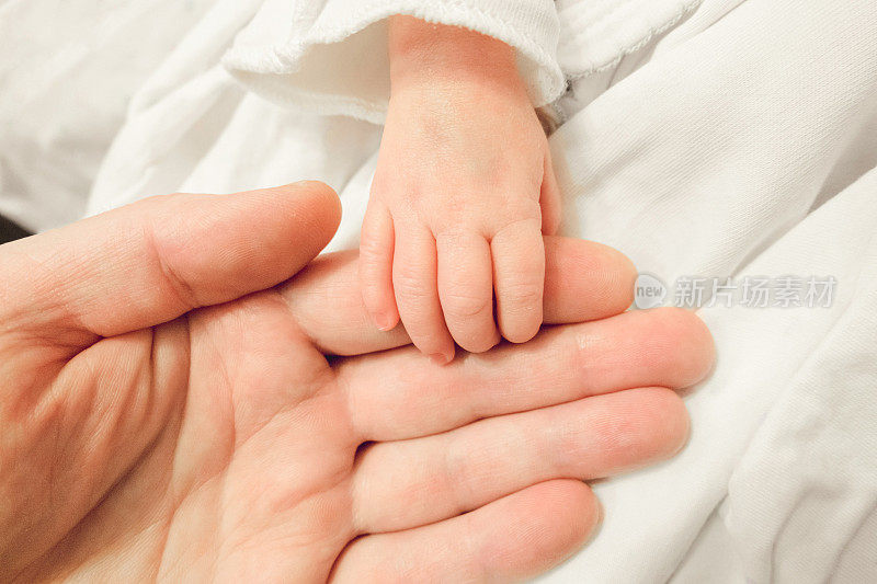 新生儿握着父亲的手指。图为新生儿的小手放在dadâ的手上。特写镜头。